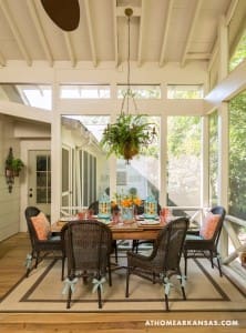 White screened porch with dining table and chairs, hanging light fixture.
