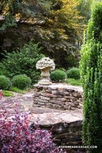 Stone urn and shrubs in a landscaped garden setting.
