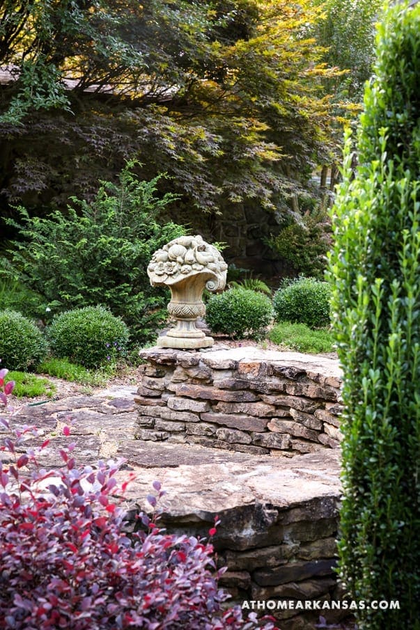 Stone urn and shrubs in a landscaped garden setting.