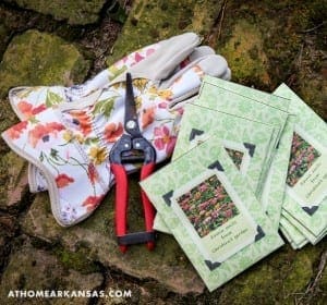 Floral glove, gardening shears, and seed packets on stone.