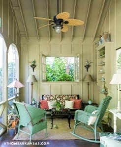 Green wicker chairs and a sofa in a screened porch.