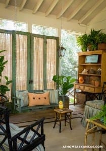 Porch with green shutters, swing, and potted plants.