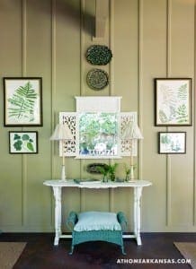 White console table with framed botanical prints and lamps.