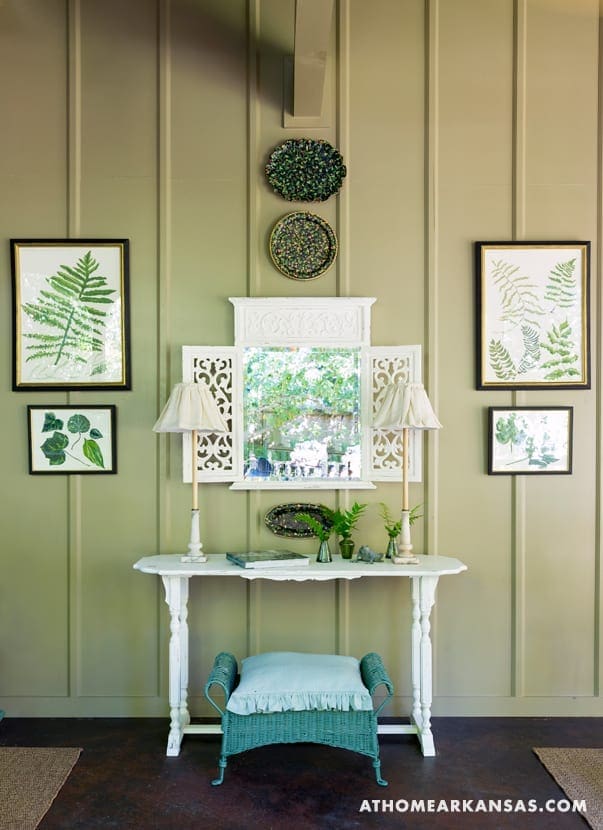 White console table with framed botanical prints and lamps.