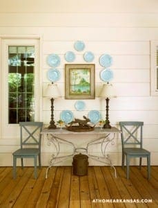 White-painted wood paneling, blue plates, and iron chairs.