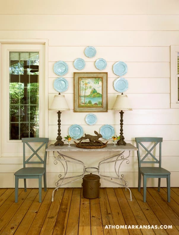 White-painted wood paneling, blue plates, and iron chairs.