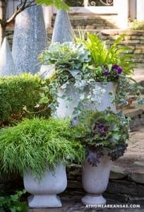 Gray urns filled with varied foliage and flowers.