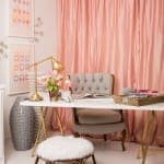 Pink curtain, desk, chair, and artwork in a home office.