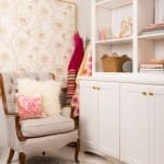 White bookcase with patterned wallpaper and upholstered armchair.