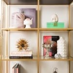 Gold shelving unit displays books, vases, and decorative objects.