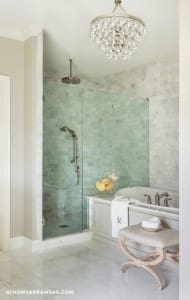 Marble tile shower with glass enclosure and chandelier.