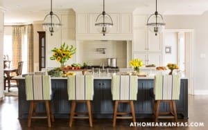 White kitchen island with gray seating and a large central sink.