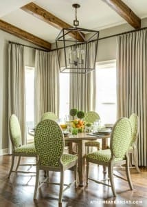 Dining area with wooden beams, beige curtains, and patterned chairs.