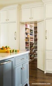 White kitchen cabinets with a blue island and pantry.