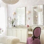 White bathroom with marble vanity, mirror, and chandelier.