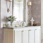 White vanity with silver mirror and sconces.