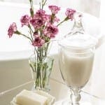 Pink carnations in a glass vase with a sugar bowl.