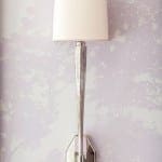 Silver wall sconce on lavender textured wall.