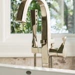 Chrome faucet with sprayer on white countertop.