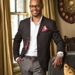 Man in a gray plaid suit, eyeglasses, and watch.