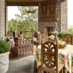 Stone porch with wooden beams, fireplace, and seating.