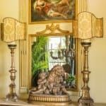 Gold-toned lamps and mirror above a marble console table.