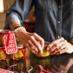 Woman wrapping gifts with red ribbons and tags.