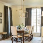 Gold chandelier hangs above a wooden dining table with upholstered chairs.