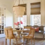 Wooden dining table with rattan blinds and a chandelier.