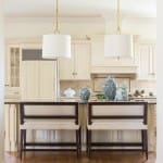 Cream cabinets, island, and bar stools in a light kitchen.