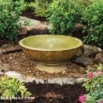 Stone fountain with water feature in garden setting.