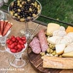 Cheese and charcuterie display on a stone table.