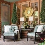 Wooden porch with chairs, lamps, and a sunburst mirror.