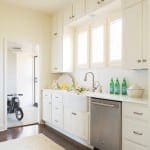 White kitchen with stainless steel appliances and a window.