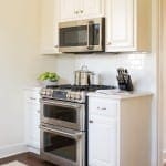 White kitchen cabinets with stainless steel microwave and range.