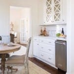 White kitchen island with stainless steel dishwasher and glassware.