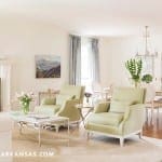Light green armchairs, wooden floor, and a dining table in a living room.