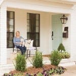 White brick house with a teal front door and porch.