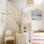 White staircase hall with a table, chair, and light fixture.