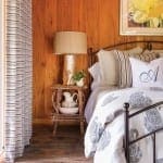 Wooden-paneled bedroom with a bed, lamp, and curtains.