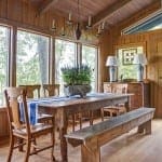 Wooden dining room with a large table, benches, and windows.