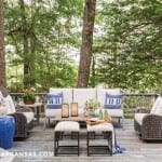 Deck with outdoor furniture, blue accents, and pine trees.