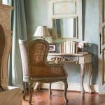 Pale green wall with ornate mirror and chair.