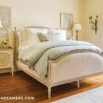 Cream-colored upholstered bed with white linens and a pale blue throw.