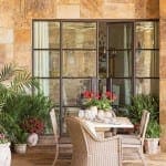 Stone exterior wall with large, dark-framed windows and outdoor furniture.