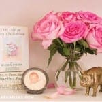 Pink roses, book, framed baby photo, and pig figurine.