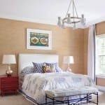 Bedroom with textured beige wallpaper, a chandelier, and a bed.