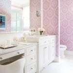 Pink wallpapered bathroom with marble vanity and mirror.