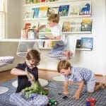 Two boys playing with toys on a rug in a child’s room.