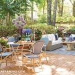 Brick patio with outdoor seating, blue and white striped rug, and floral arrangements.